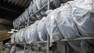 Ogumienie do aut na półkach, zapakowane w białe worki foliowe na opony